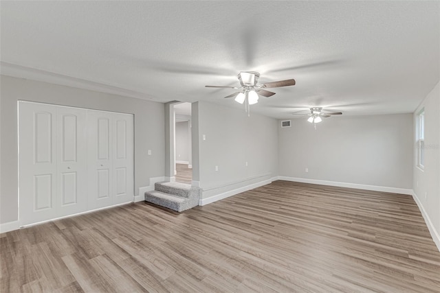 interior space featuring light wood-style flooring, visible vents, baseboards, and a textured ceiling