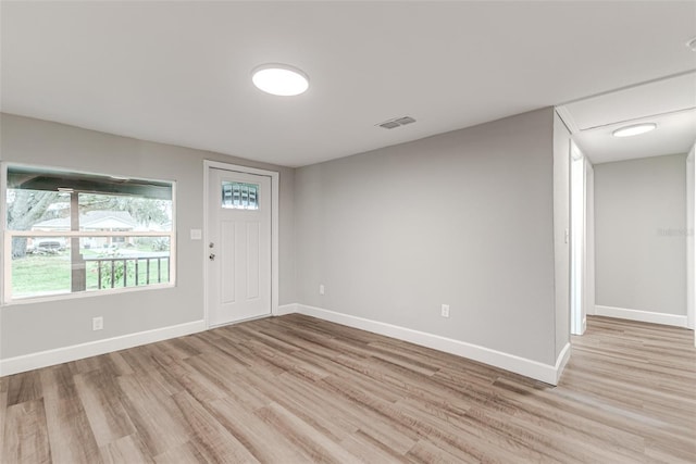 foyer entrance featuring visible vents, light wood-style flooring, and baseboards