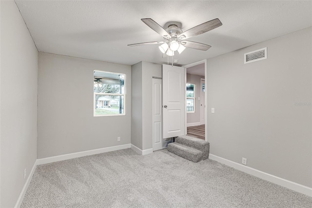 unfurnished bedroom featuring light colored carpet, visible vents, baseboards, and a textured ceiling