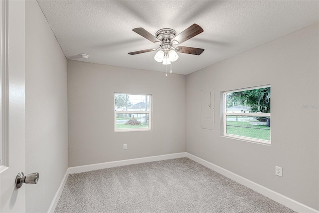 carpeted spare room featuring ceiling fan, baseboards, and a textured ceiling