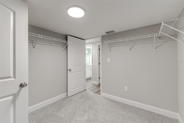 walk in closet with light colored carpet and visible vents