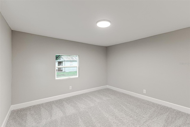 carpeted empty room featuring baseboards