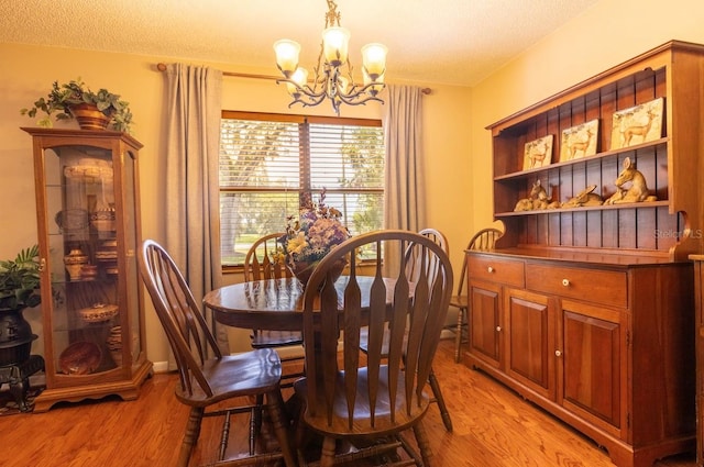 dining area featuring a textured ceiling, a chandelier, and light hardwood / wood-style floors