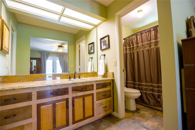 bathroom with vanity, toilet, a shower with shower curtain, and ceiling fan