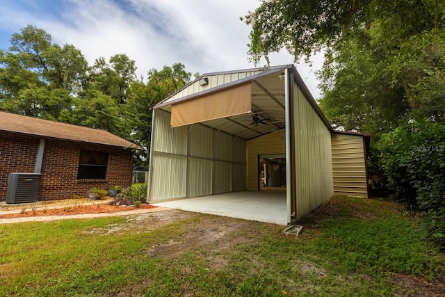 view of outbuilding featuring a lawn, a carport, and cooling unit