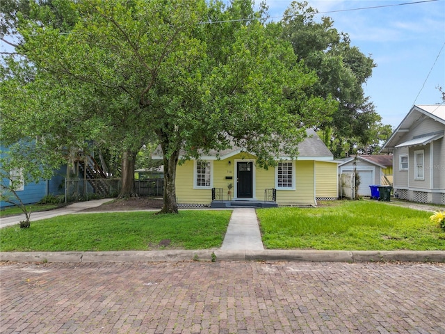 view of front of house with a front yard, fence, and an outbuilding