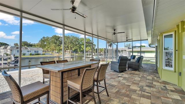 sunroom / solarium with a water view and ceiling fan