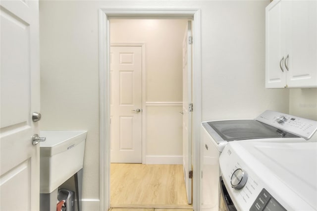 washroom with light wood-type flooring, cabinets, and independent washer and dryer