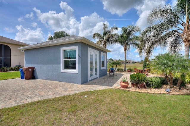 view of property exterior with french doors, a yard, and a patio