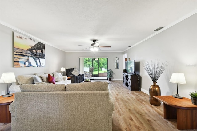 living area featuring a ceiling fan, visible vents, baseboards, light wood-style floors, and crown molding