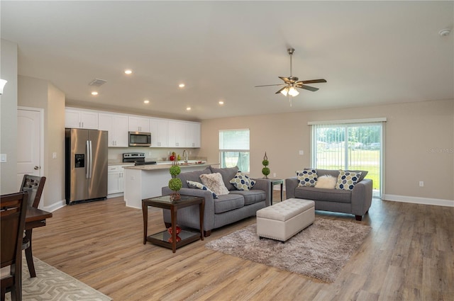 living room with ceiling fan, sink, and light hardwood / wood-style floors