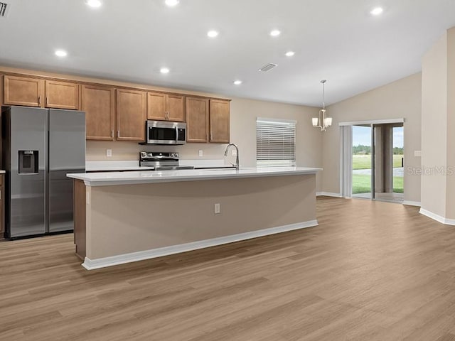 kitchen featuring lofted ceiling, a kitchen island with sink, hanging light fixtures, light wood-type flooring, and stainless steel appliances