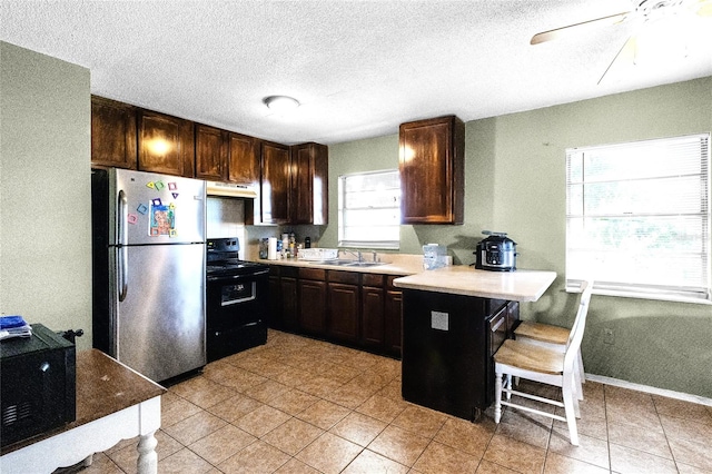 kitchen with a breakfast bar, stainless steel refrigerator, kitchen peninsula, sink, and electric range