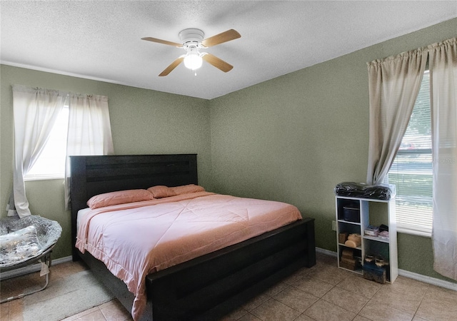 bedroom featuring a textured ceiling, light tile patterned floors, and ceiling fan