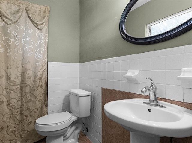 bathroom with sink, tile walls, and toilet