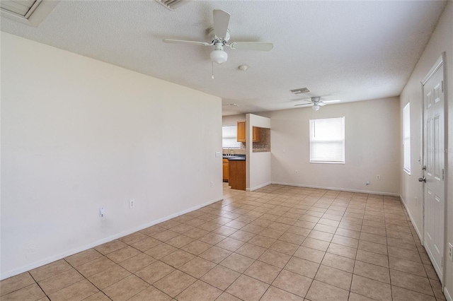 tiled empty room featuring ceiling fan and a textured ceiling