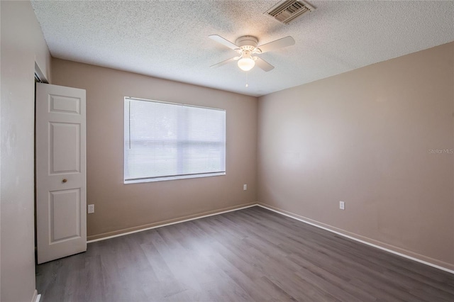 empty room with ceiling fan, dark hardwood / wood-style floors, and a textured ceiling