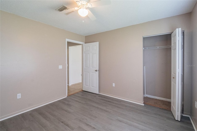 unfurnished bedroom with a textured ceiling, hardwood / wood-style floors, ceiling fan, and a closet