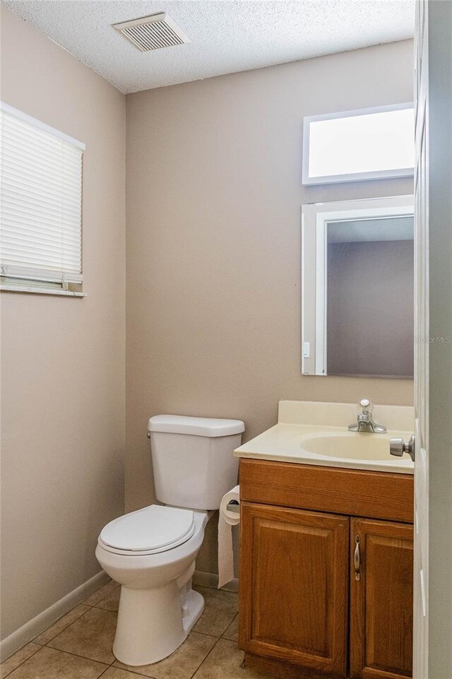 bathroom featuring vanity, toilet, tile patterned floors, and a textured ceiling