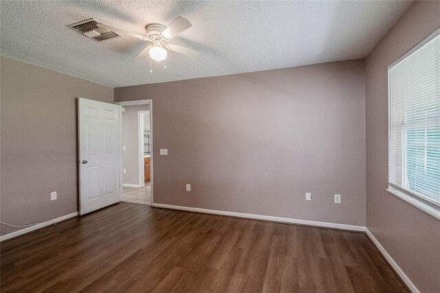 empty room with dark hardwood / wood-style flooring, ceiling fan, and a textured ceiling