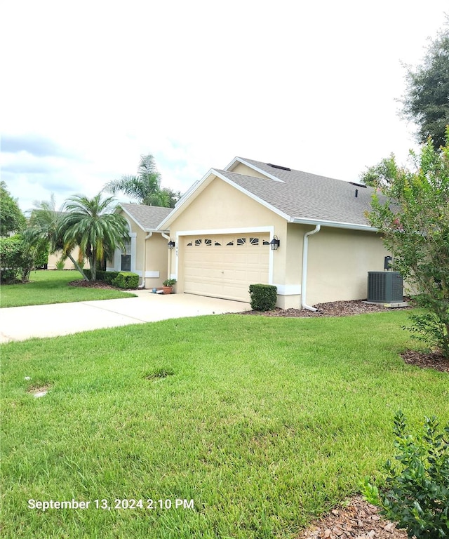 view of front of home with a front lawn, a garage, and central AC