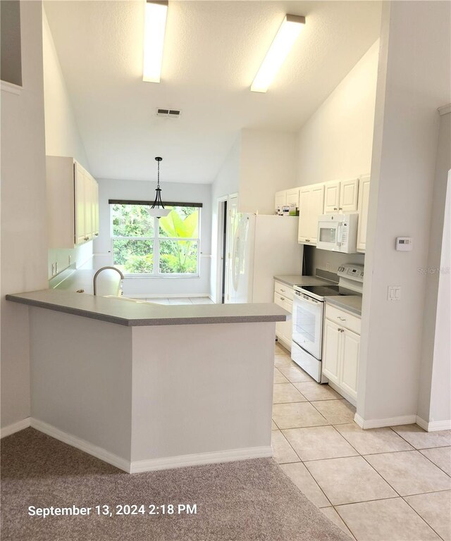 kitchen featuring lofted ceiling, kitchen peninsula, and white appliances