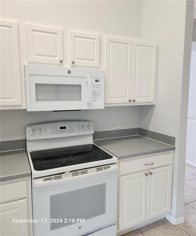 kitchen featuring light tile patterned floors, white appliances, and white cabinetry