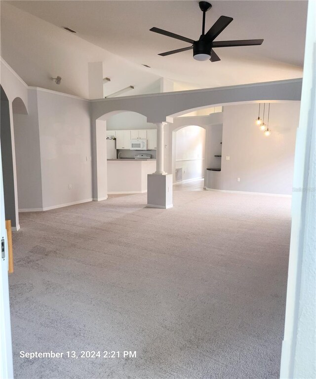 unfurnished living room with light colored carpet, vaulted ceiling, and ceiling fan