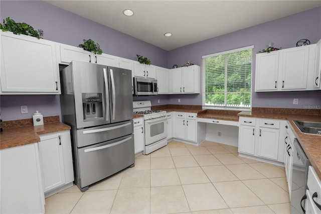 kitchen with white cabinets, appliances with stainless steel finishes, sink, and light tile patterned flooring