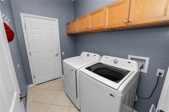 washroom with cabinets, washing machine and dryer, and light tile patterned flooring