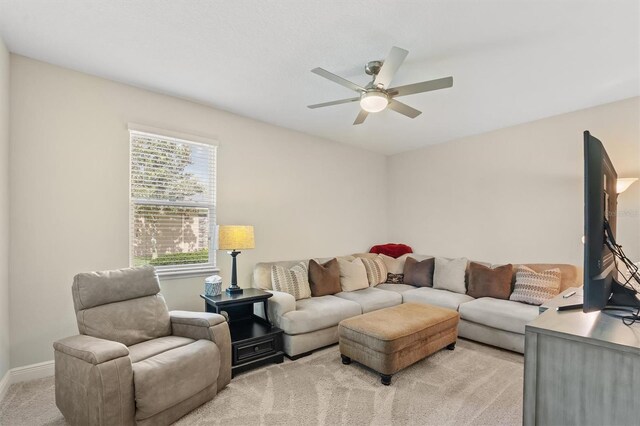 living room featuring light colored carpet, ceiling fan, and baseboards