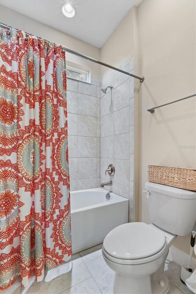 bathroom with toilet, baseboards, shower / bath combo with shower curtain, and tile patterned floors