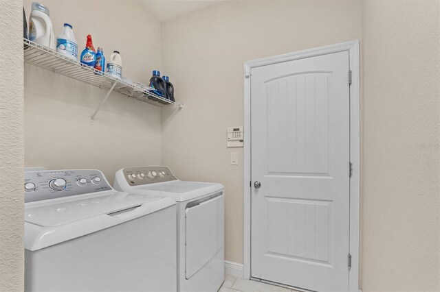 washroom featuring laundry area, washer and clothes dryer, and light tile patterned floors