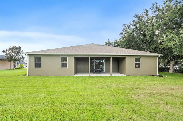 rear view of property with a yard, roof with shingles, a patio, and stucco siding