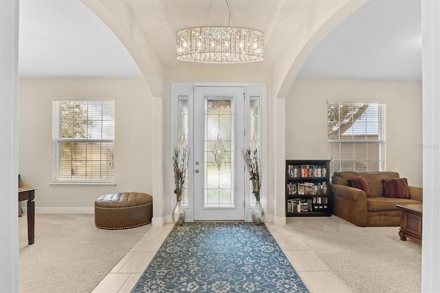 entrance foyer featuring a wealth of natural light, light colored carpet, arched walkways, and light tile patterned floors