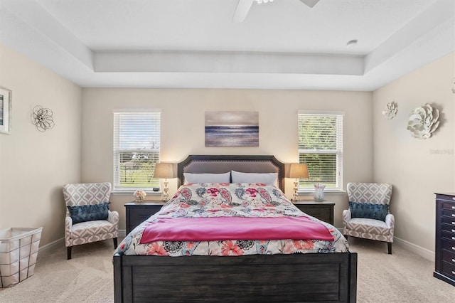 bedroom with light carpet, baseboards, and a tray ceiling