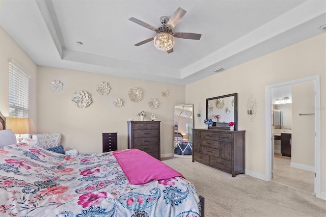 bedroom featuring light carpet, a tray ceiling, and baseboards