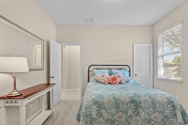 bedroom with baseboards, visible vents, and light colored carpet