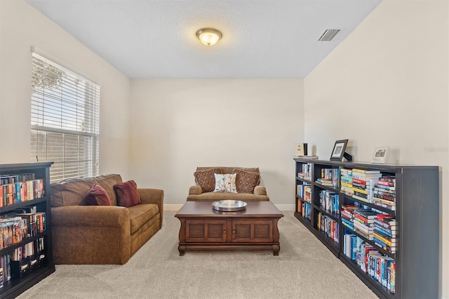 living area featuring a textured ceiling, carpet flooring, visible vents, and baseboards