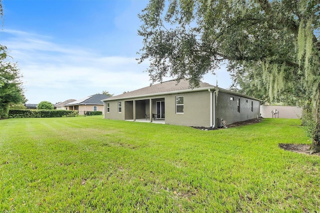 back of property featuring a lawn, a patio area, fence, and stucco siding