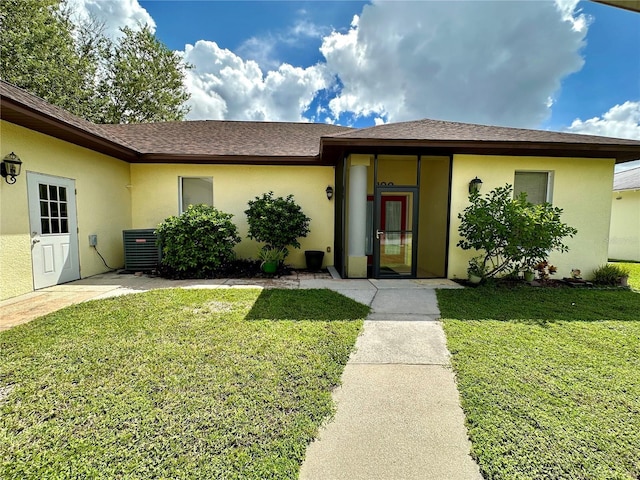 ranch-style house with stucco siding, central AC, and a front lawn