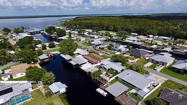 drone / aerial view featuring a residential view, a wooded view, and a water view