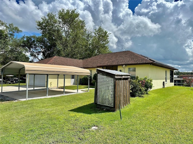 exterior space featuring a detached carport, a lawn, roof with shingles, and stucco siding