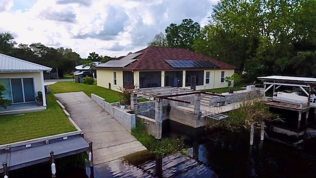 rear view of house with roof mounted solar panels and a lawn