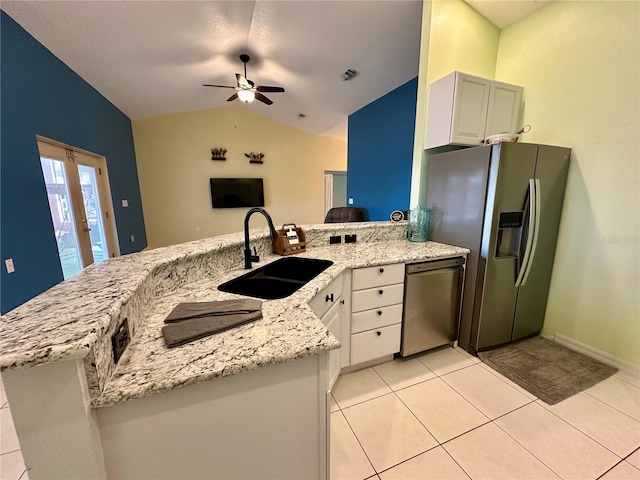 kitchen with a sink, light stone counters, stainless steel appliances, a peninsula, and vaulted ceiling