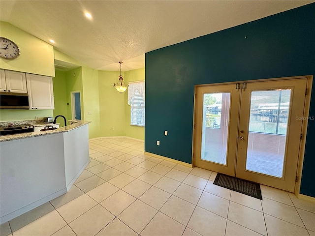 kitchen featuring light tile patterned flooring, hanging light fixtures, white cabinets, and appliances with stainless steel finishes