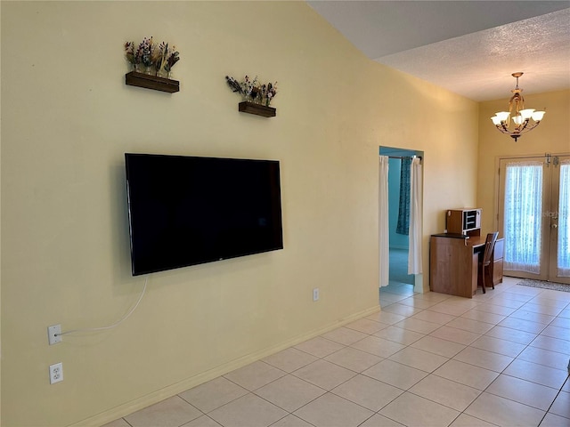 unfurnished living room featuring a notable chandelier, a textured ceiling, french doors, light tile patterned floors, and baseboards