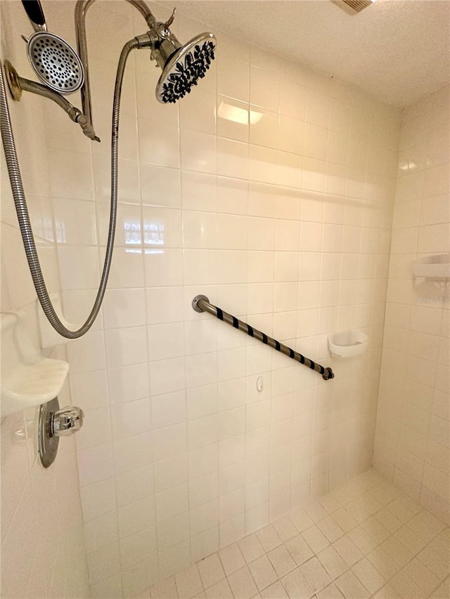 bathroom with a textured ceiling and a tile shower