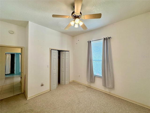 unfurnished bedroom featuring a textured ceiling, ceiling fan, a closet, and carpet flooring