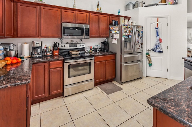 kitchen with dark stone countertops, light tile patterned flooring, and appliances with stainless steel finishes